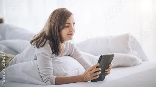 Attractive woman reacted with joy on the bed while she was playing tablet