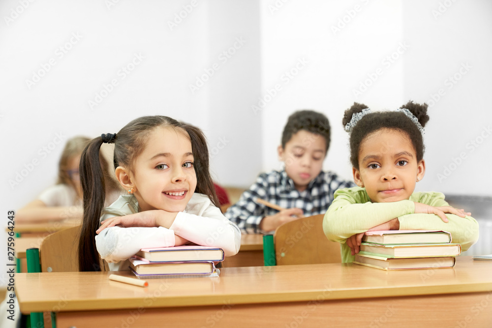 Two charming students sitting at table in school and posing Two charming students sitting at table in school and posing