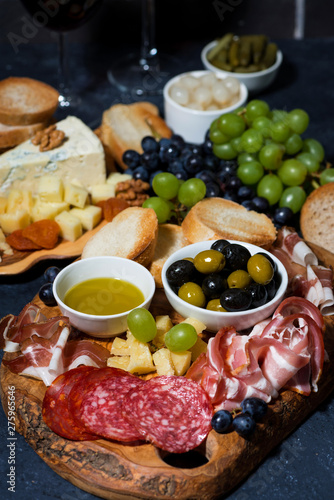 two glasses of red wine and assorted gourmet cheeses, fruit and meats, closeup