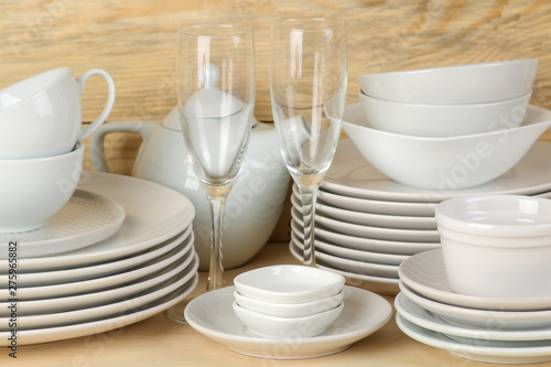 Piles of white ceramic tableware, plates, saucers and cups on a natural wooden background. kitchenware.