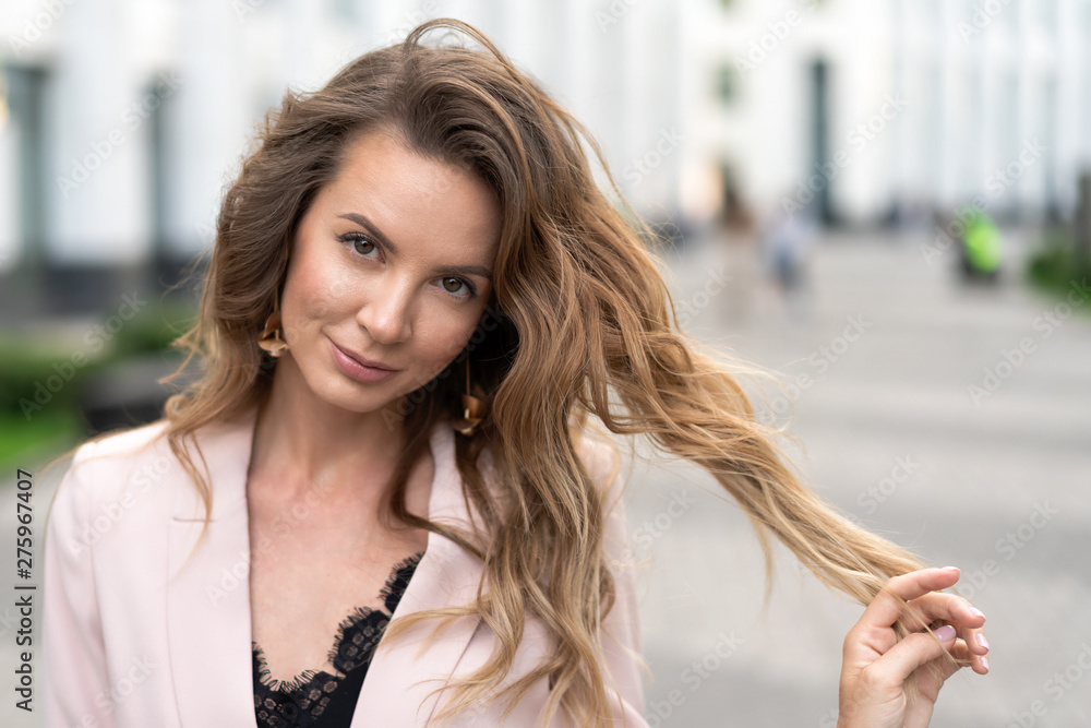 Obraz premium portrait of a girl with long wavy hair, a very beautiful face and an attractive smile. Street close-up in good summer weather. A great option for advertising.