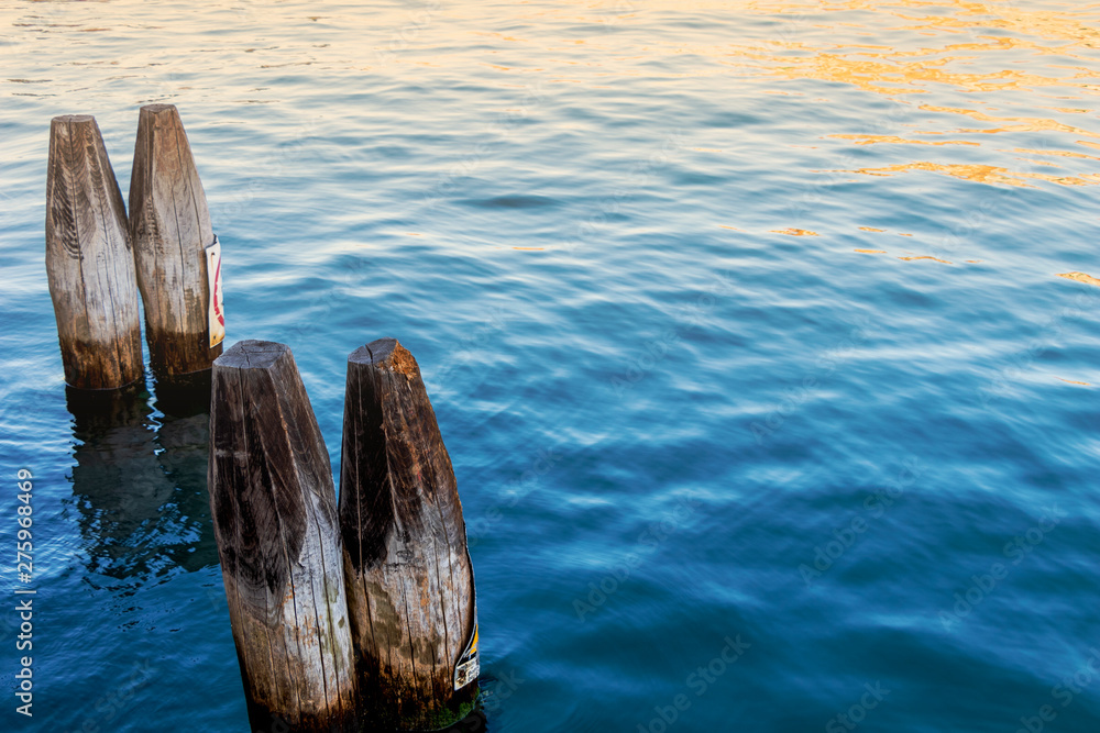 close up of wooden pillars on the blue sea with sun light in the morning. close up of wooden pillars on the blue sea with sun light in the morning.