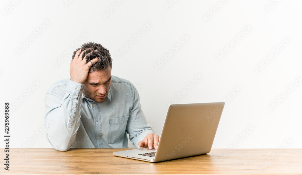 Young handsome man working with his laptop tired and very sleepy keeping hand on head. Young handsome man working with his laptop tired and very sleepy keeping hand on head.