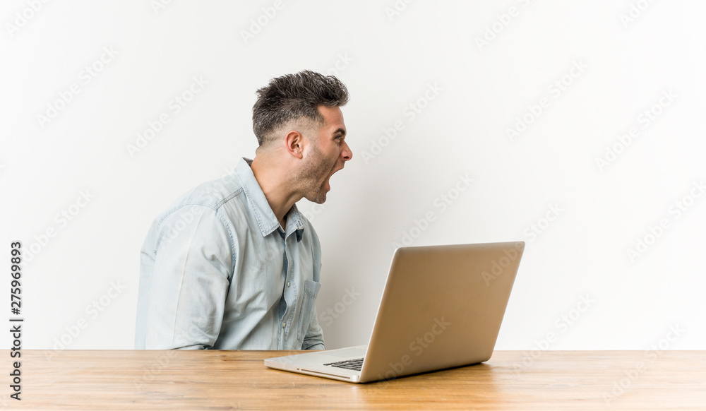 Young handsome man working with his laptop shouting towards a copy space Young handsome man working with his laptop shouting towards a copy space