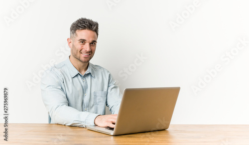 Young handsome man working with his laptop happy, smiling and cheerful.