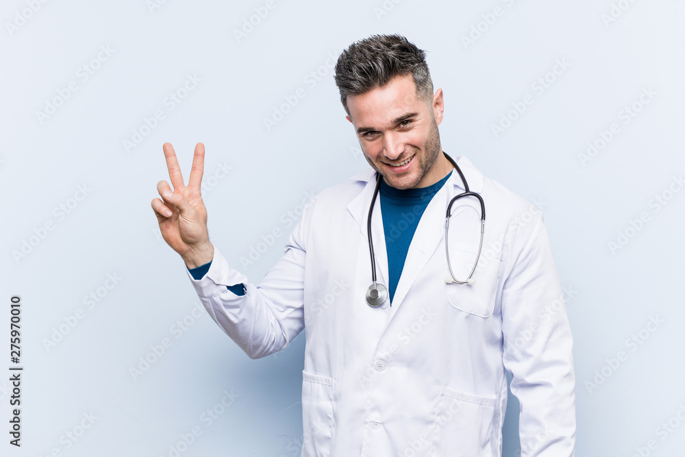 Young handsome doctor man joyful and carefree showing a peace symbol with fingers. Young handsome doctor man joyful and carefree showing a peace symbol with fingers.