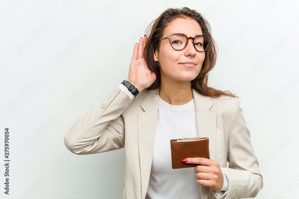 Young european business woman holding a wallet trying to listening a gossip. Young european business woman holding a wallet trying to listening a gossip.