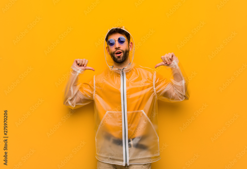 Young man wearing a rain coat pointing fingers, example to follow Young man wearing a rain coat pointing fingers, example to follow