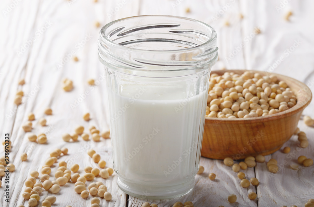 Non-dairy alternative Soy milk or yogurt in mason jar on white wooden table with soybeans in bowl aside Non-dairy alternative Soy milk or yogurt in mason jar on white wooden table with soybeans in bowl aside