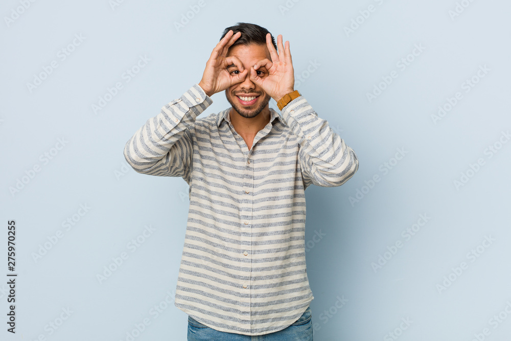 Young handsome filipino man showing okay sign over eyes Young handsome filipino man showing okay sign over eyes