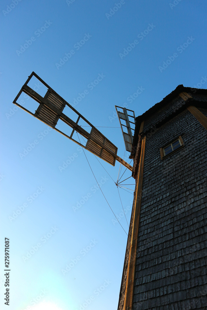 Old wooden windmill with blue sky on the background view from below Old wooden windmill with blue sky on the background view from below