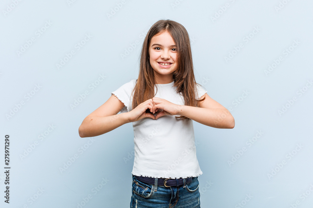 Cute girl smiling and showing a heart shape with him hands. Cute girl smiling and showing a heart shape with him hands.