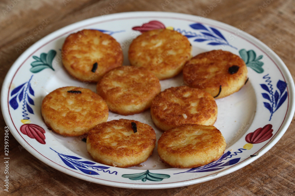 fresh baked hommade potato pancakes, also named rosti, hash browns, kartoffelpuffer, latkes, draniki - on white plate on wooden background.