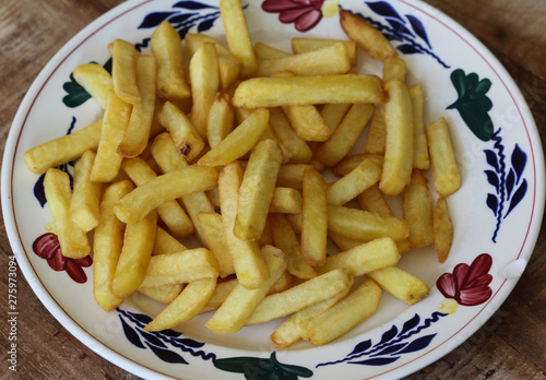 Tasty homemade french fries on white plate, on wooden table background