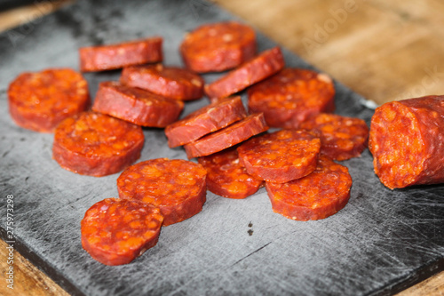 Fresh made Spanish pork chorizo sausages made with paprika, garlic, chilli and rosemary, sliced on a black cutting board photo