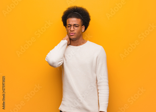 Young african american man over an orange wall suffering neck pain