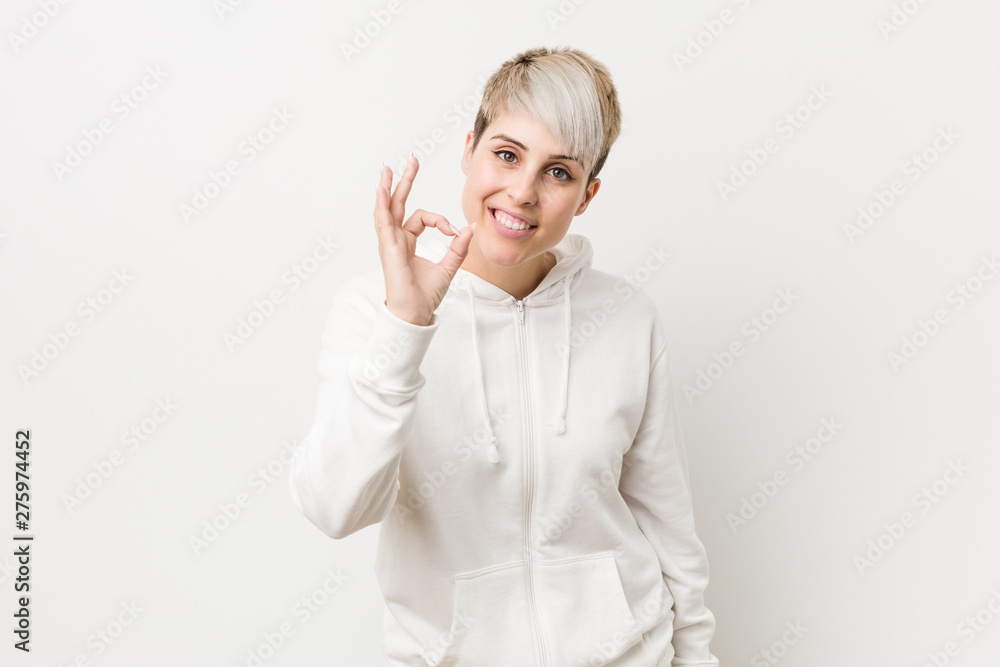 Young curvy woman wearing a white hoodie cheerful and confident showing ok gesture. Young curvy woman wearing a white hoodie cheerful and confident showing ok gesture.