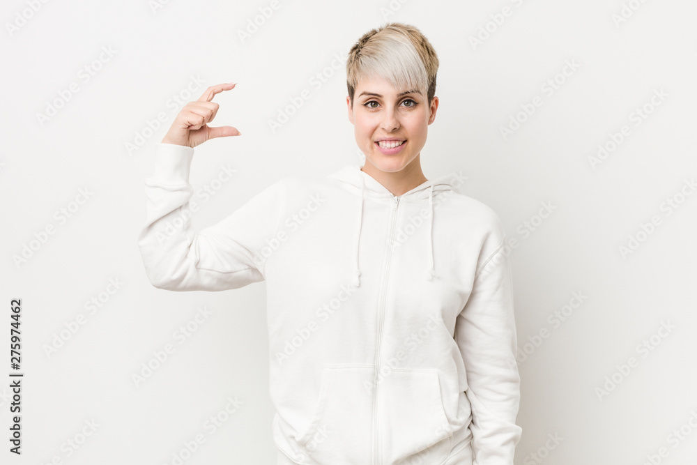 Young curvy woman wearing a white hoodie holding something little with forefingers, smiling and confident. Young curvy woman wearing a white hoodie holding something little with forefingers, smiling and confident.