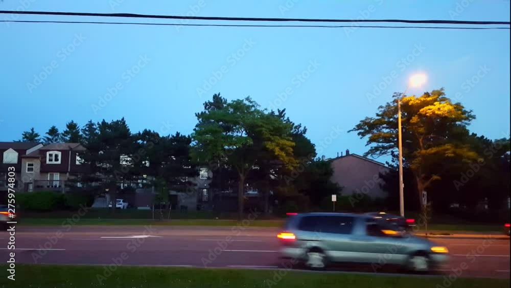 Side View of City Road Traffic Driving at Night. City Life Urban Landscape With Street Light at Evening Dusk. Side View of City Road Traffic Driving at Night. City Life Urban Landscape With Street Light at Evening Dusk.