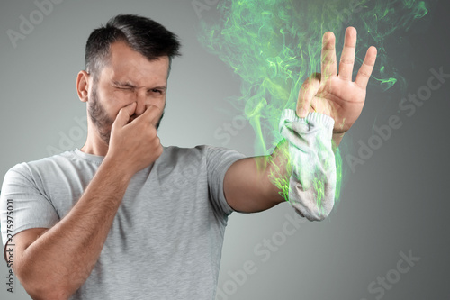 Картината върху платно A young man holds his smelly socks and covers his nose with his hand