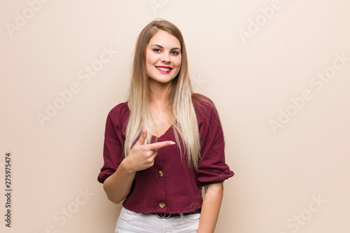 Young russian woman smiling and pointing to the side © Asier