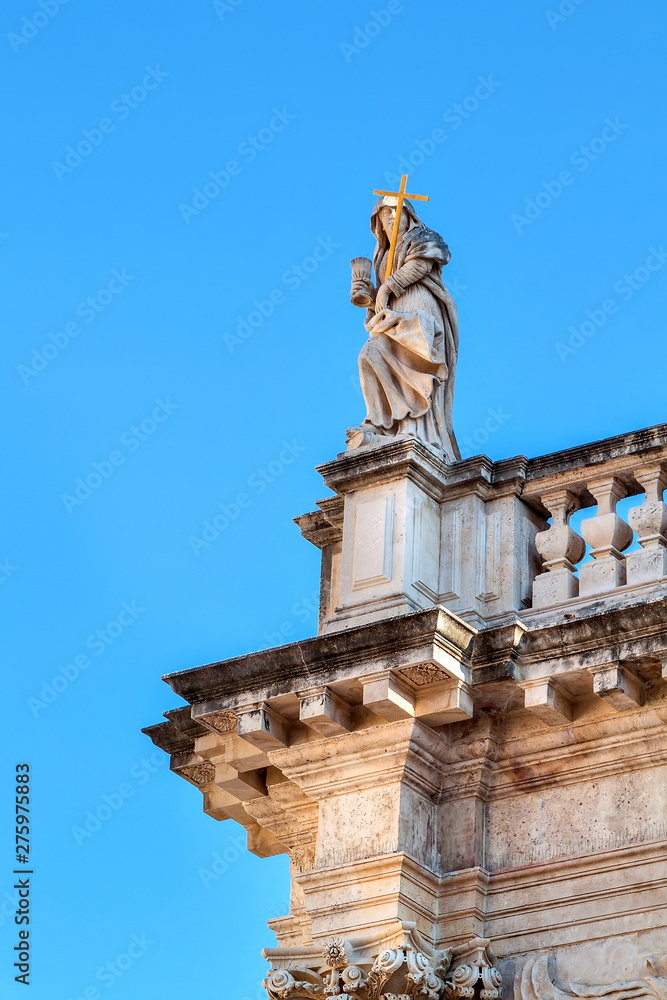 Sculpture of a woman with a cross on the roof of an old church. Dubrovnik, Croatia