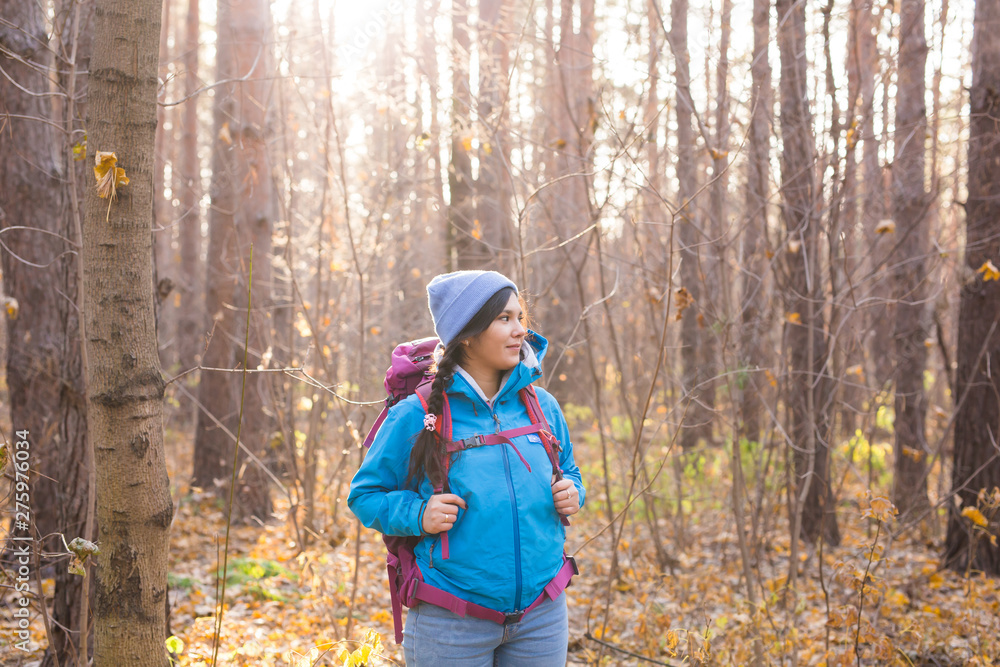 adventure, travel, tourism, hike and people concept - smiling tourist woman walking with backpacks over autumn natural background