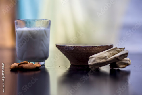 Face mask of multani mitti or mulpani mitti or fuller's earth in a clay bowl on the wooden surface well mixed with milk and almonds. For the treatment of softer skin. photo