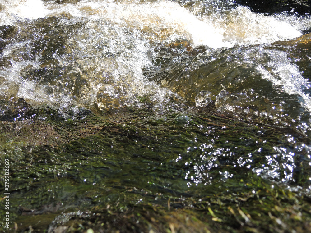 Fototapeta premium Rapid flow of water flows through large rocks