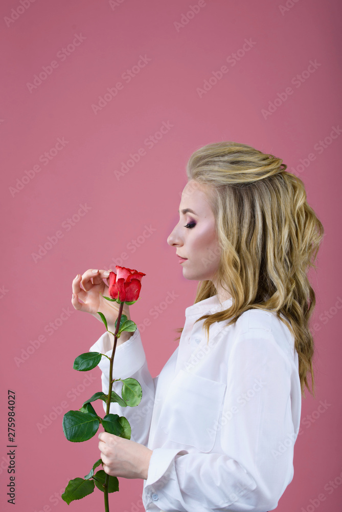 Beautiful portrait of a girl on a pink background with yellow flower near the face Beautiful portrait of a girl on a pink background with yellow flower near the face
