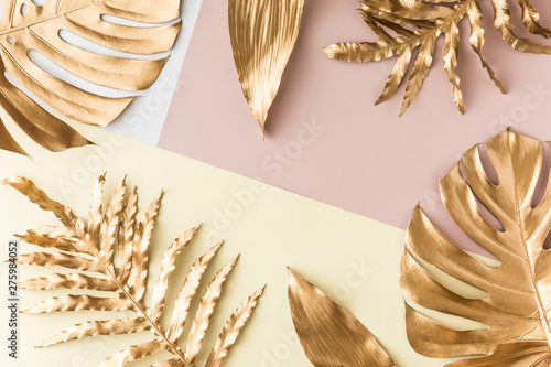 Flat lay of gold tropical palm leaves Monstera on pastel background. Top view...