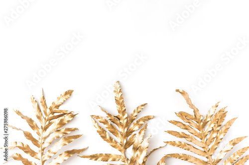 Flat lay of gold tropical palm leaves Monstera on white background. Top view of minimal concept.