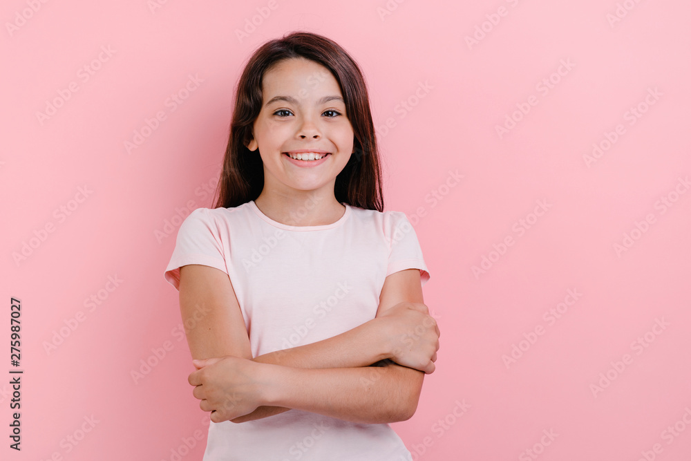 Obraz premium Little girl standing with folded her hands over pink background