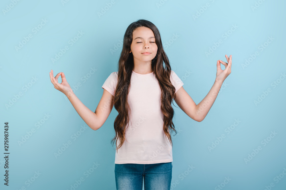 Girl standing in meditation pose over blue studio background. - Image Girl standing in meditation pose over blue studio background. - Image