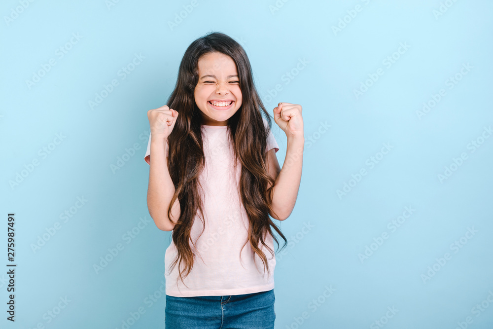 Happy child girl with closed eyes holds fists up in winner gesture- Image Happy child girl with closed eyes holds fists up in winner gesture- Image
