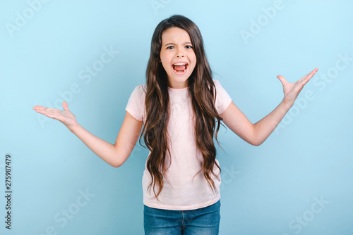 Girl screaming with hands apart in botn side over blue background . - Image photo