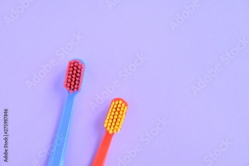 Two bright toothbrushes with soft focus on blurred purple background. Plastic toothbrush for personal daily oral hygiene. Dental healthcare. Tools for morning routine. Caries protection