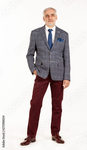 Portrait of smart and handsome intelligent senior man in stylish grey jacket and dark red pants isolated on white background