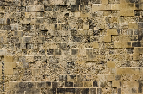 Old and weathered beige limestone brick wall