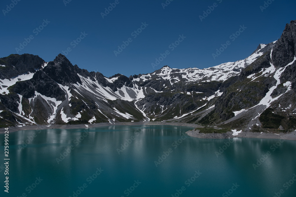 Stausee in Vorarlberg mit schneebedeckten Bergen