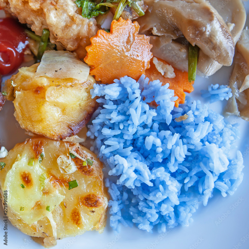 Purple steamed rice with potatoes and vegetables on white plate. Purple steamed rice with potatoes and vegetables on white plate.