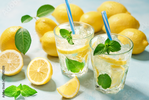 two glasses of lemonade with fresh lemon on turquoise background. Top view