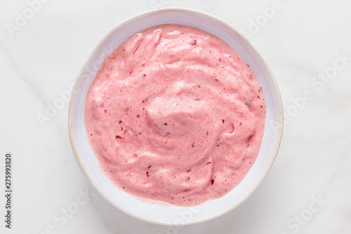 nice cream or smoothie bowl made of frozen bananas and berries on white marble table. healthy breakfast