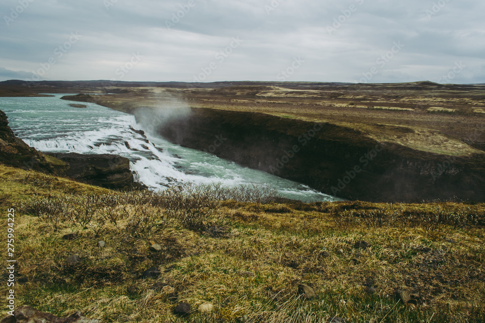 Gullfoss, one of the most beautiful destinations in Iceland. Pale green grass and cascades with turquoise water.