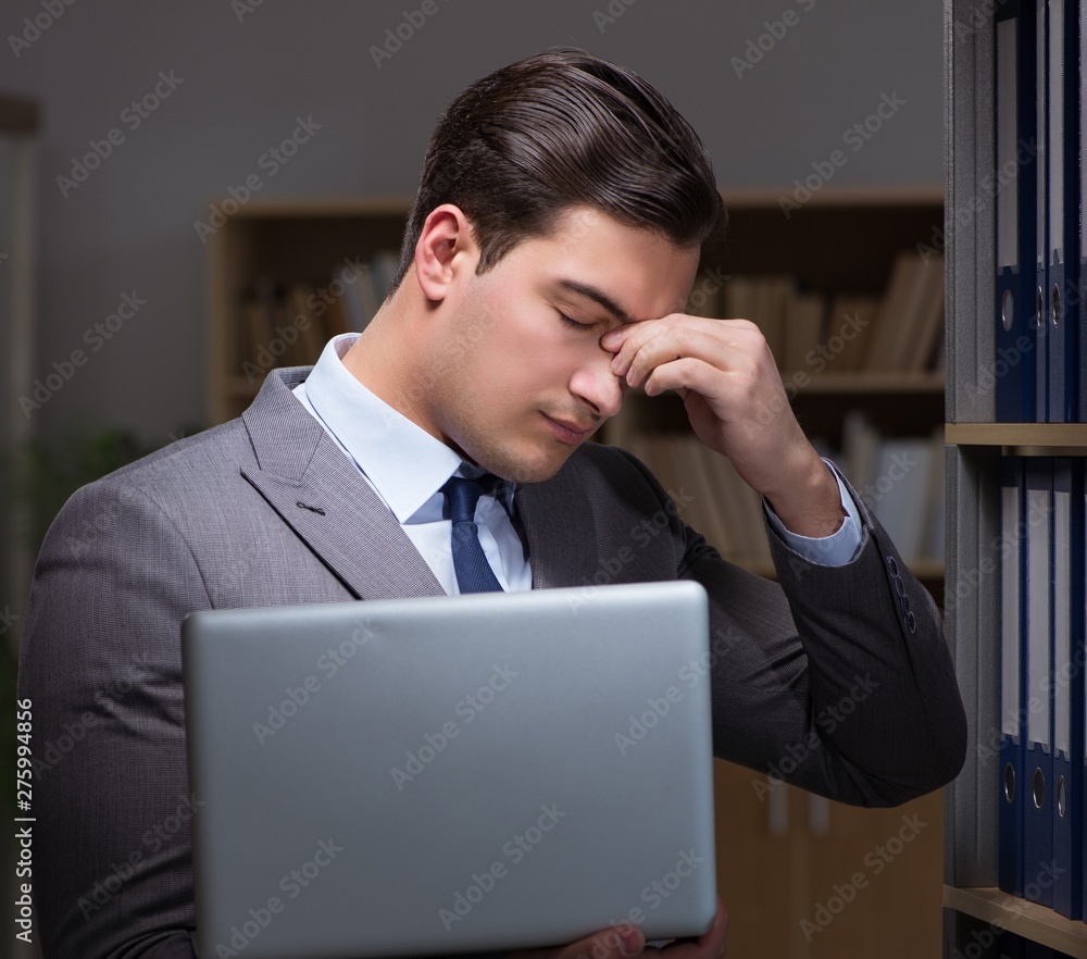 Businessman almost falling asleep working late hours in the offi Businessman almost falling asleep working late hours in the offi