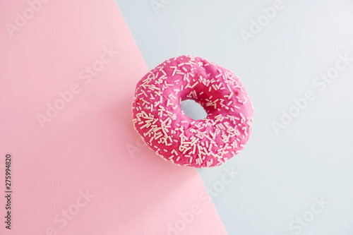 Juicy Pink Sprinkled Donut isolated on a Pink and Blue Background