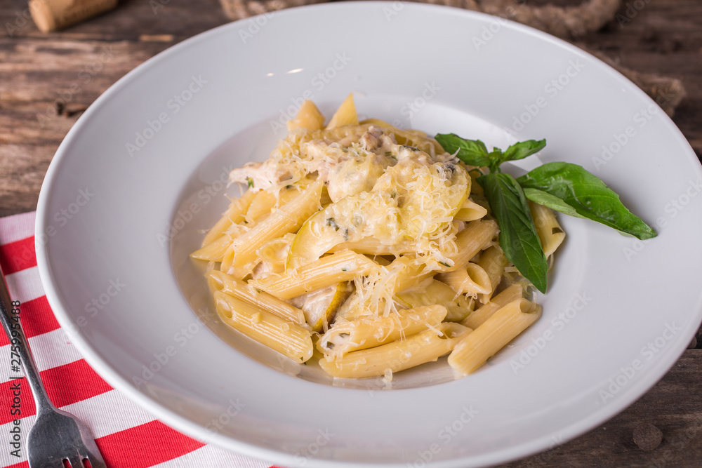 Delicious creamy Italian penne pasta starter with pepper seasoning and fresh basil on rustic wooden table Delicious creamy Italian penne pasta starter with pepper seasoning and fresh basil on rustic wooden table