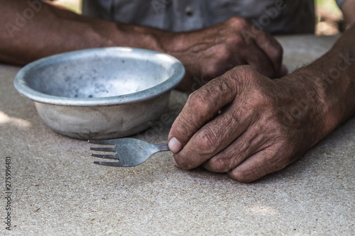 Hungry. Poor old man's hands an empty bowl. Selective focus. Poverty in retirement. Alms