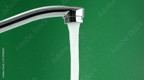 water flows from the tap on a green background, splashes are visible