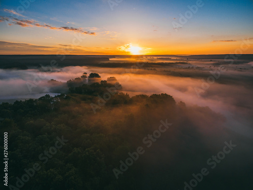 Sunrise over spring meadow. Spring aerial landscape. Spring sunrise over green forest and field with river and fog.